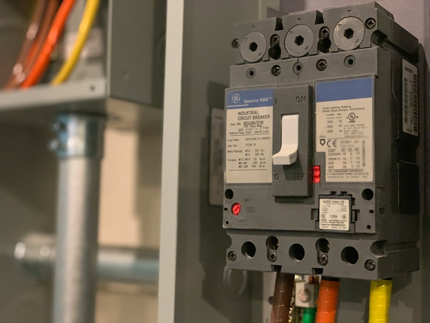 Industrieller Leistungsschalter mit bunten Kabeln in einem Schaltschrank.